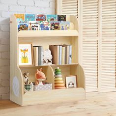 a wooden book shelf with books and toys on it in front of a brick wall