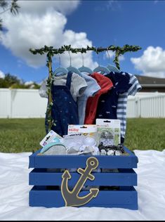 a blue crate filled with baby clothes and an anchor