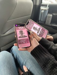 two people sitting in the back seat of a car holding up their cell phones with pictures on them