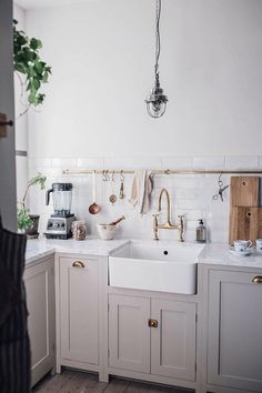 a kitchen with white cabinets and gold faucets