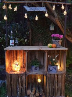 an outdoor bar made out of wooden pallets with lights on top and flowers in the back