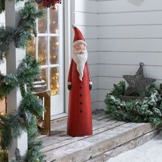 a red santa clause statue sitting on top of a porch