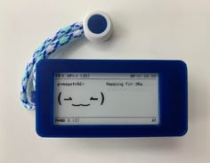 an electronic device with a face drawn on the screen next to a cord that is attached to it