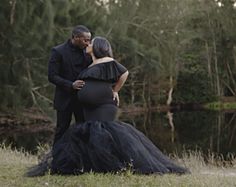 a pregnant woman in a black gown standing next to a man