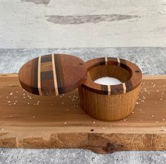 a wooden bowl sitting on top of a cutting board next to a container filled with sugar