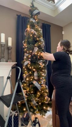 a pregnant woman decorating a christmas tree