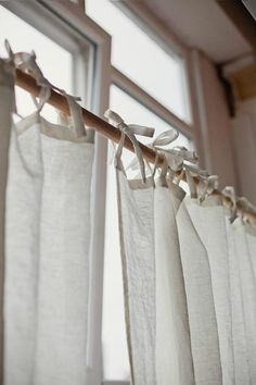 the curtains are hanging in front of the window with white linens on them and tied together