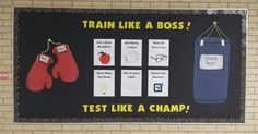 a bulletin board with boxing gloves and an apple hanging from it's side, which reads train like a boss test like a champ?