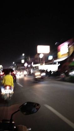 a man riding a motorcycle down a street at night