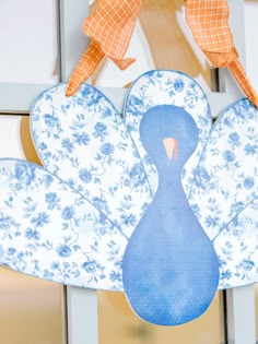 a paper turkey hanging from a door with ribbon around it's neck and an orange bow at the top