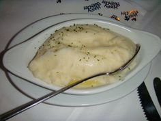 two mashed potatoes on a white plate with a spoon