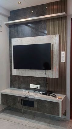 an entertainment center with a flat screen tv mounted on the wall and wires plugged into it