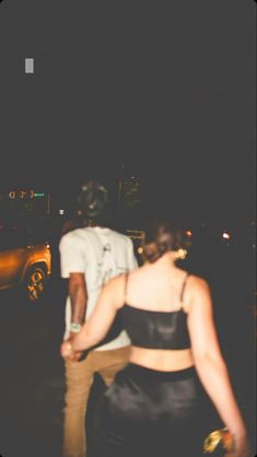 two people walking in the street at night with one person holding his hand out to him