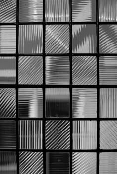 black and white photo of glass tiles with different patterns on the wall in an office building