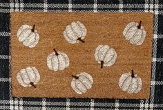 a brown door mat with white pumpkins on it