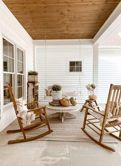 a porch with rocking chairs and potted plants