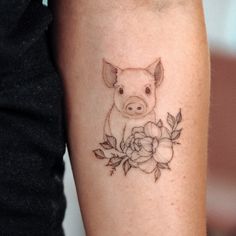 a small pig on the arm with flowers and leaves around it's neck is shown