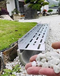 someone is holding something in their hand near the grass and rocks that are laying on the ground