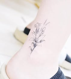 a small flower tattoo on the ankle is shown in black and grey ink, while it's still attached to a woman's foot