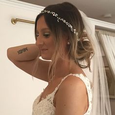 a woman in a wedding dress with a veil on her head and tattoos on her arm