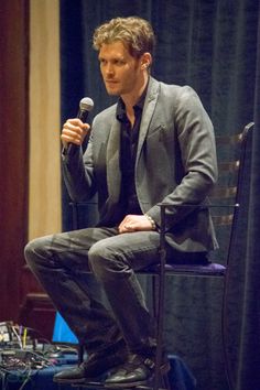 a man sitting in a chair holding a microphone