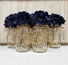 four glass jars with blue flowers in them