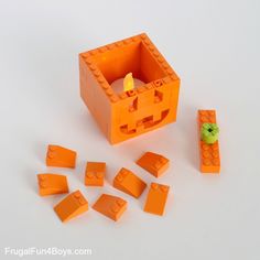 an orange lego set with pieces missing from the box and one green piece in the middle