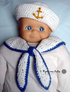 the doll is wearing a white coat and hat with a blue ribbon around it's neck