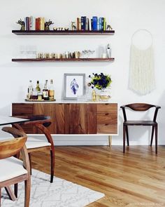 a dining room table with chairs and shelves on the wall