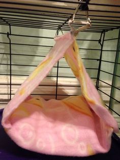 a hamster cage with a pink and yellow blanket hanging from it