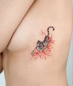 a woman's breast with a tiger tattoo on her left side and red ink