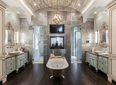 a large bathroom with two sinks and a tub in front of a tv mounted on the wall