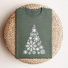 a green t - shirt with white snowflakes on it sitting next to a wicker basket