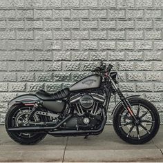 a black motorcycle is parked in front of a wall with silver bricks on it's sides