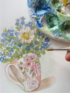 someone is painting flowers in a vase with watercolors