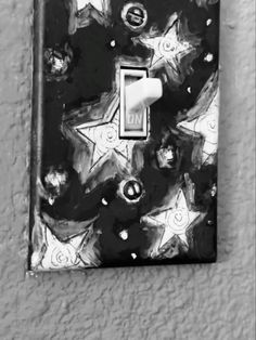 a black and white photo of a light switch cover with stars on the wall behind it