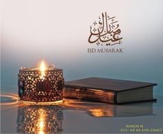 a lit candle sitting on top of a table next to an open book with the word eid mubarak written in arabic