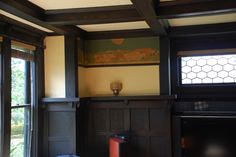 a living room with wood paneling and large windows, along with a painting on the wall