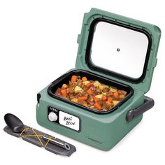 a green and black portable food warmer with spoons next to it on a white background