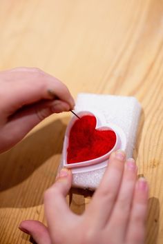 someone is making a heart shaped box with red felt