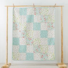 a patchwork quilt hanging on a wooden frame in front of a white wall and floor