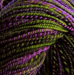 purple and green yarn is shown in this close up photo, with the end of it's skeins visible