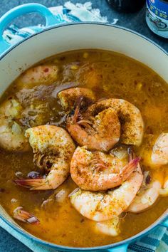 a bowl filled with soup and shrimp on top of a blue towel next to a bottle