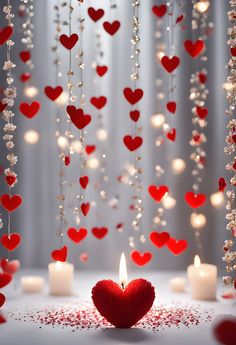 a red heart shaped candle surrounded by white candles with hearts hanging from the strings and beads