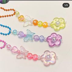 three necklaces with flowers and butterflies on them, one is multicolored the other has beaded beads