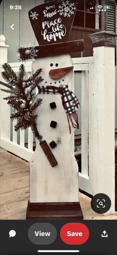 a snowman with a hat and scarf on it's head standing in front of a house