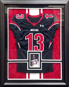 a football jersey is displayed in a black frame with a red and white stripe around it