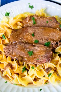 some meat and noodles on a white plate