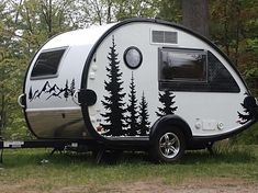 an rv parked in the woods with trees painted on it