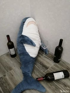 a stuffed shark laying on the floor next to wine bottles